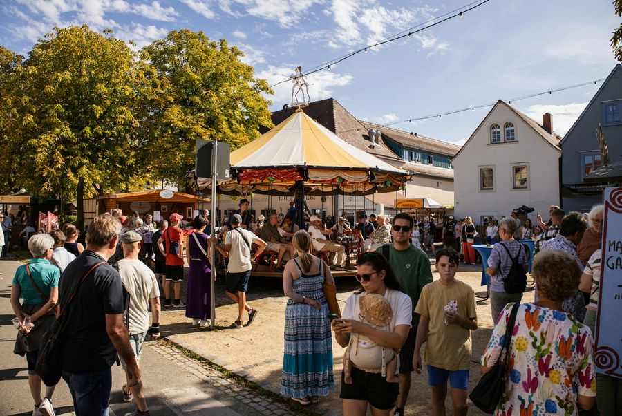 Traditional carousel ride at a town fair, surrounded by visitors on a sunny afternoon