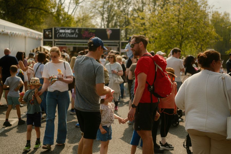 Families walking past an ice cream and cold drinks stall at a busy food festival