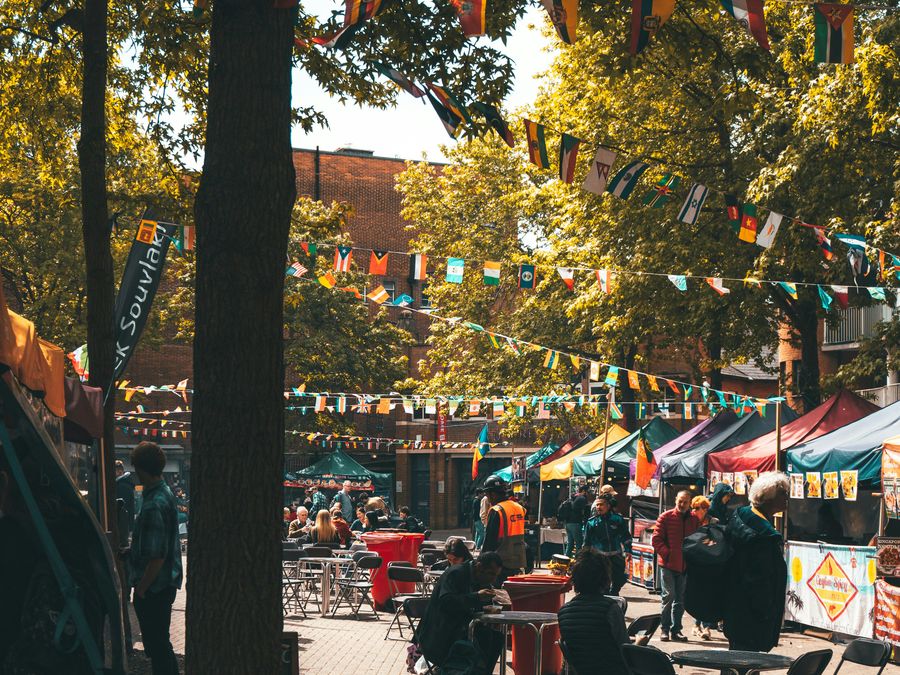 Street food market with gazebo stalls, flag bunting and a steward in a hi-vis vest